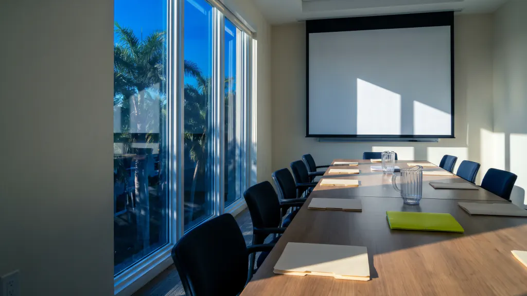 An empty condo association meeting room with chairs around a table and a blank projector screen.