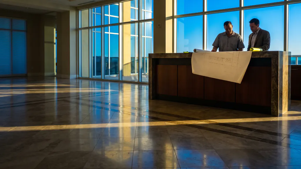 An installer and a building manager review a drawing at a condo lobby counter.